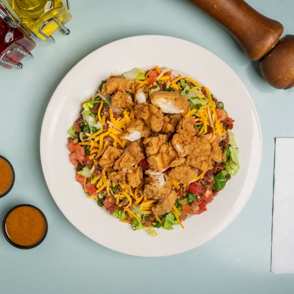 Lucille's American Cafe's fried chicken salad with cheese, tomatoes, and bacon bits.