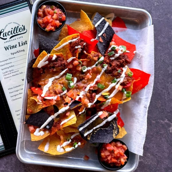 Lucille's American Cafe nachos with chili, cheese, sour cream, and salsa on a metal tray.