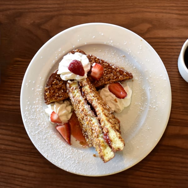 Lucille's American Cafe's French toast with strawberries, whipped cream, and powdered sugar.