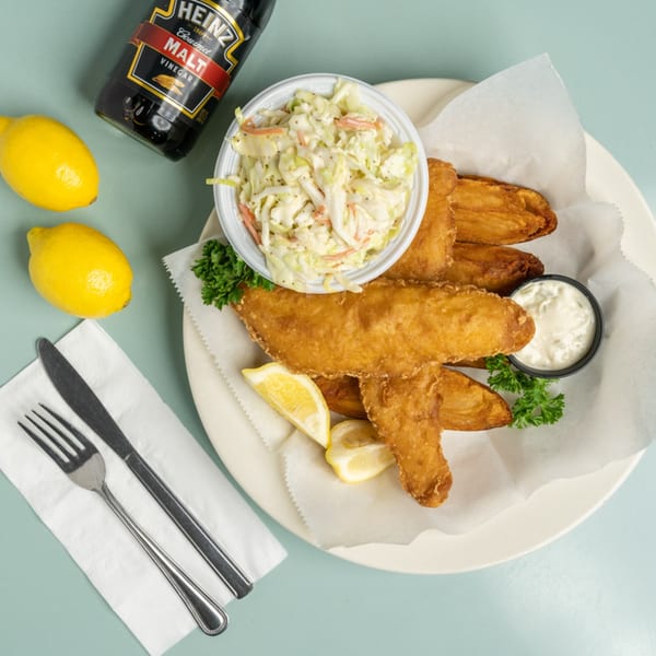 Lucille's American Cafe's fish and chips with coleslaw, tartar sauce, lemons, and malt vinegar.